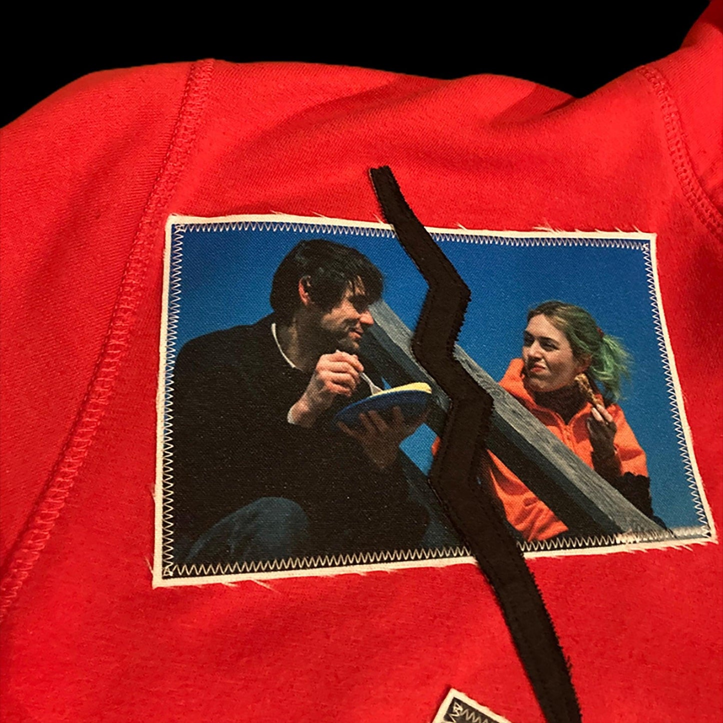 Detail of the Eternal Sunshine of the Spotless Mind patch on the Love is not real hoodie upcycled by 00timeleft.