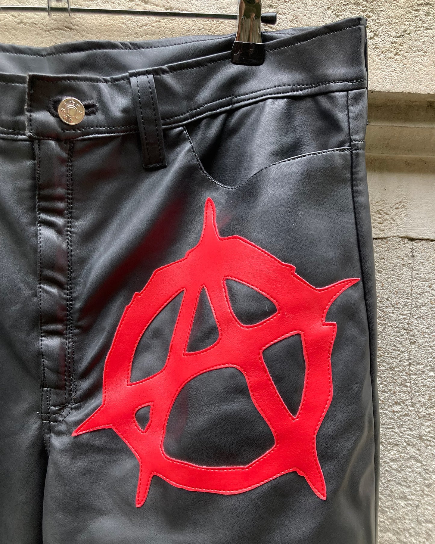 detailed view of the front logo of the anarchy pleather pants