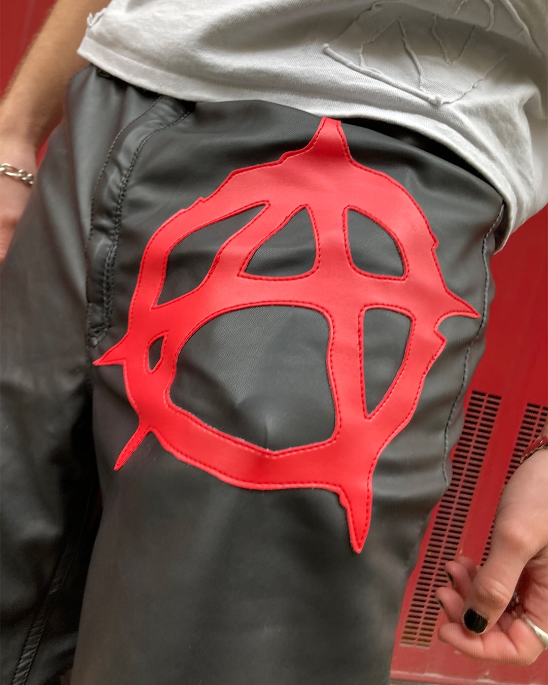 Detail view of the front logo of the anarchy pleather pants